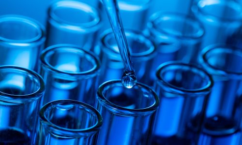 closeup-shot-pipette-tip-with-droplet-glass-test-tubes
